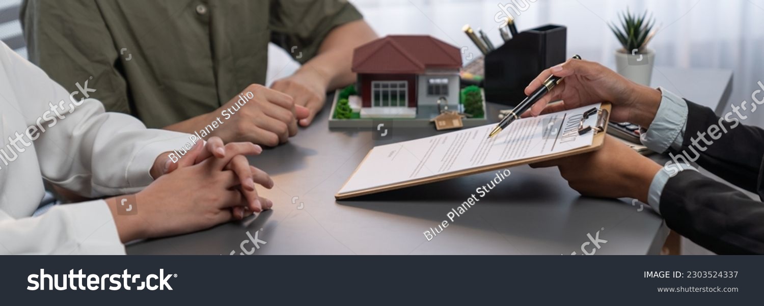 Stock photo client review loan contract with real estate agent discussing term interest and property 2303524337